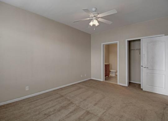 A room with a ceiling fan and carpeted floor.
