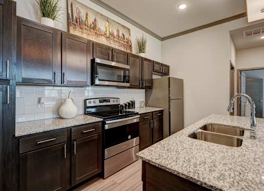 A kitchen with dark brown cabinets and a granite countertop.