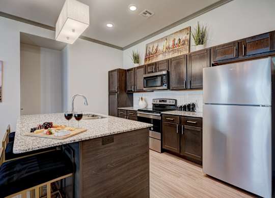 A kitchen with a stainless steel refrigerator and wooden cabinets.