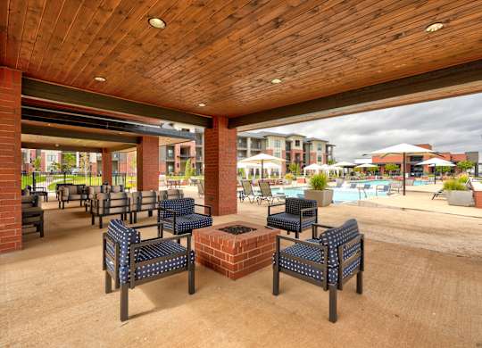 A wooden covered patio with blue cushioned seating.