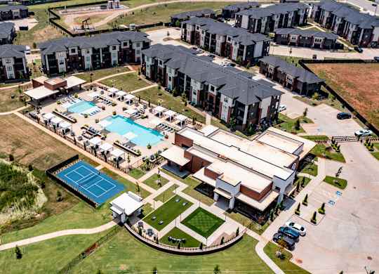 An aerial view of apartment buildings with a swimming pool and tennis court.