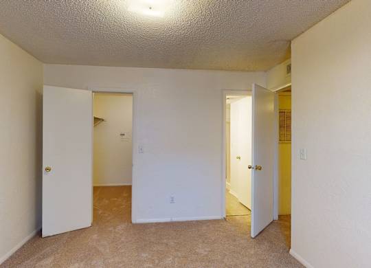 A room with a carpeted floor and two doors.
