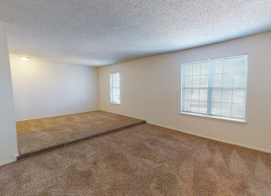 A room with a carpeted floor and a window with blinds.