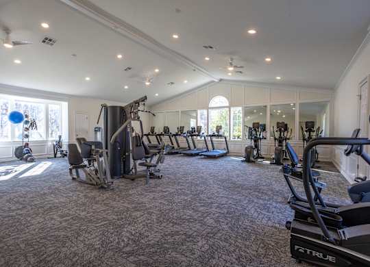 A spacious gym with a variety of equipment and a carpeted floor.