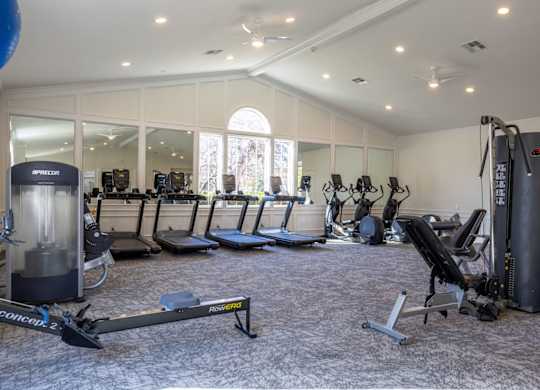 A gym with a variety of equipment including treadmills, stationary bikes, and weight machines.