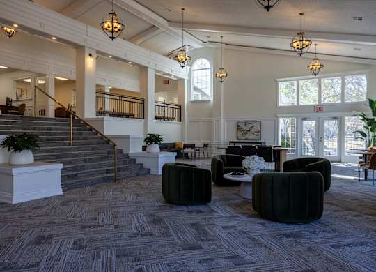 A large, well-lit room with a staircase and comfortable seating areas.