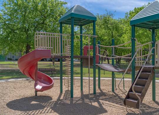 A playground with a red slide and a green roofed structure.