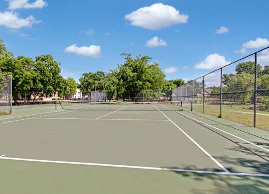 A tennis court surrounded by a fence and trees.