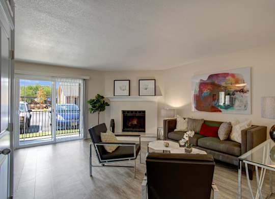 A living room with a fireplace, couch, and chairs.