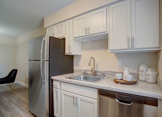 A kitchen with white cabinets and a stainless steel refrigerator.