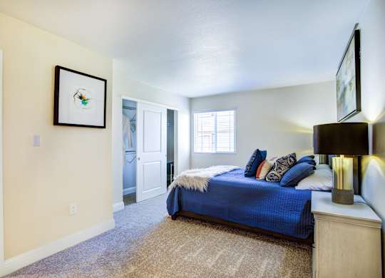 A bedroom with a blue bed and a painting on the wall.