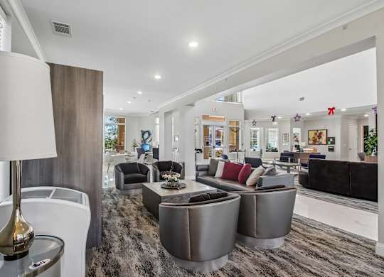 A modern living room with a grey carpet and a variety of seating options.
