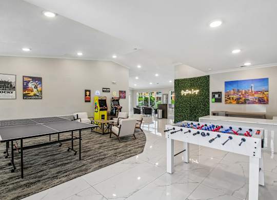 A foosball table is in the middle of a room with a ping pong table and a pool table.