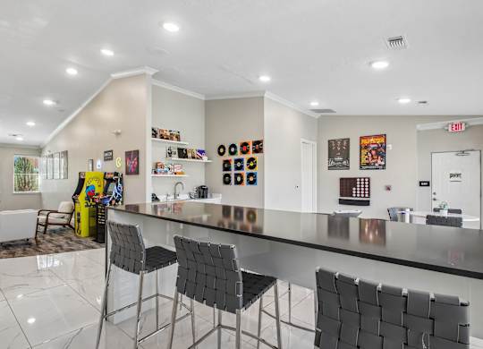 A modern kitchen with a long counter and chairs.