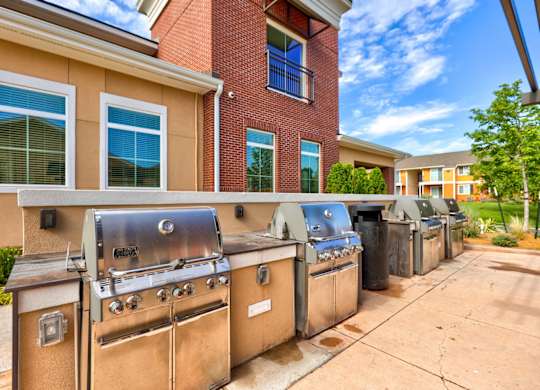A row of outdoor grills are lined up on a sidewalk.