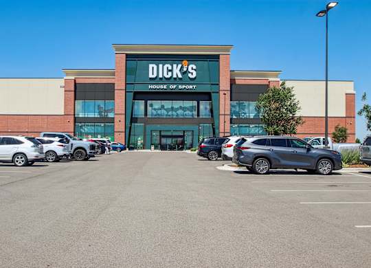 A Dick's Sporting Goods store with cars parked in front.