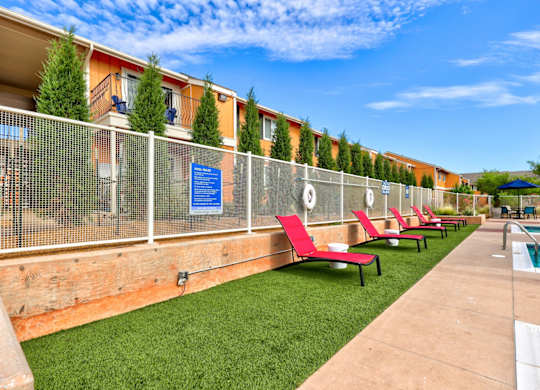 A poolside area with red chairs and a fence.
