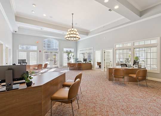 A bright leasing office here at Lincoln at Central Park with wood service desks, guest seating, and large windows with blinds. A decorative chandelier and high ceilings create an open, welcoming, and professional leasing environment.