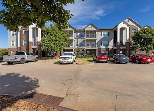 A parking lot with cars and apartment buildings in the background.