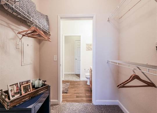 A hallway with a coat rack and a doorway leading to a bathroom.