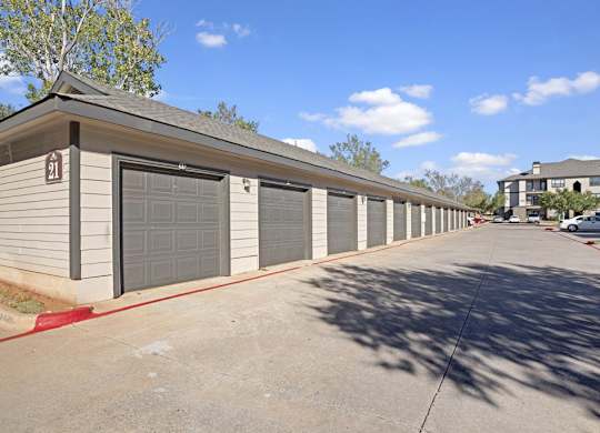 A row of detached garages here at Stoneleigh on May with individual roll-up doors and a clean paved drive. The layout offers convenient parking and extra storage in a well-maintained community setting.