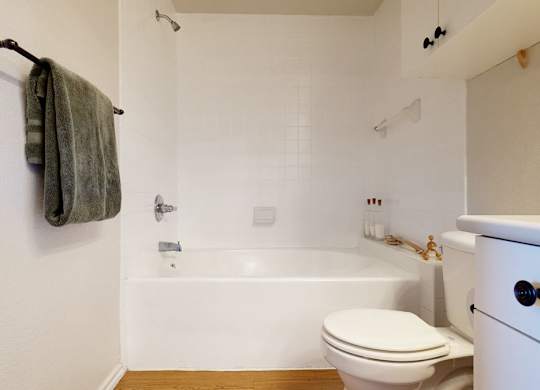 A white bathroom with a toilet, bathtub, and a towel rack.