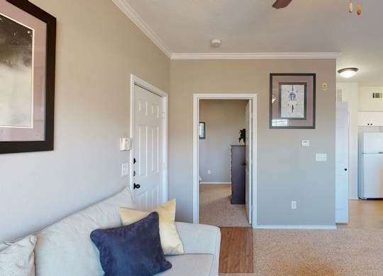 A living room with a white couch and a painting on the wall.
