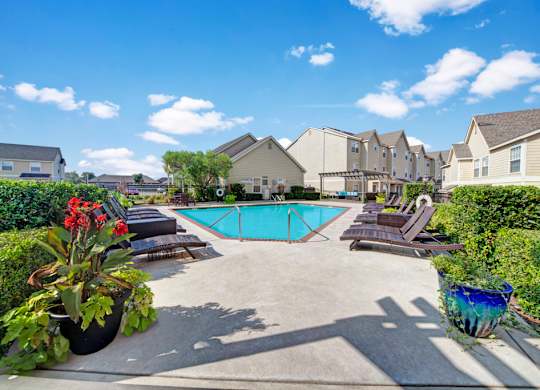 A pool surrounded by lounge chairs and plants.