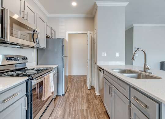 A modern kitchen with stainless steel appliances and wooden flooring.