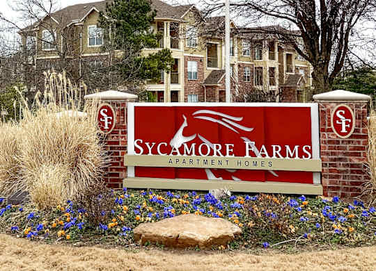 A sign for Sycamore Farms in front of a building.