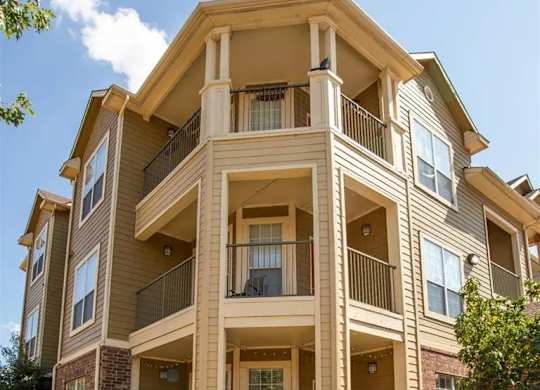 A large, two-story apartment building with balconies and multiple windows.