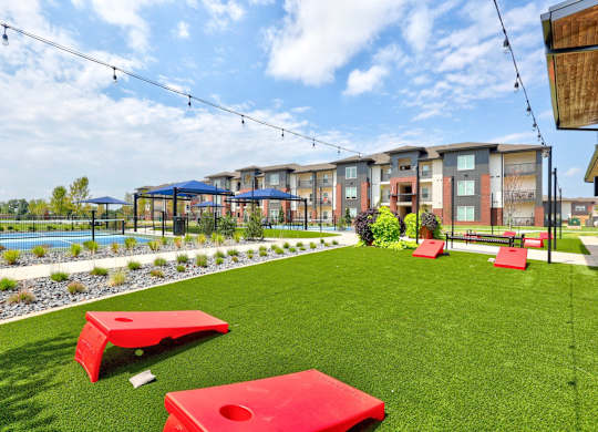 A grassy area with red benches and a pool in the background.