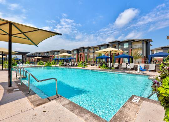 A swimming pool surrounded by a metal railing and umbrellas.
