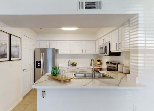 A kitchen with white cabinets and a stainless steel refrigerator.
