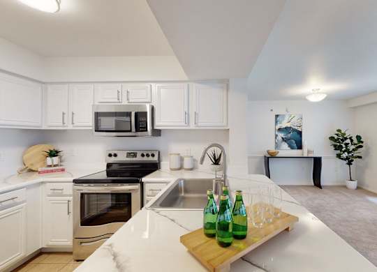 A kitchen with white cabinets and a green bottle on the counter.