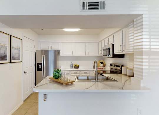 A kitchen with white cabinets and a stainless steel refrigerator.