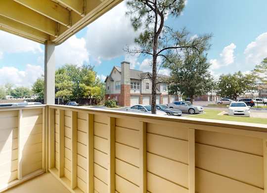 A view from a balcony looking out at a residential area with houses and cars.