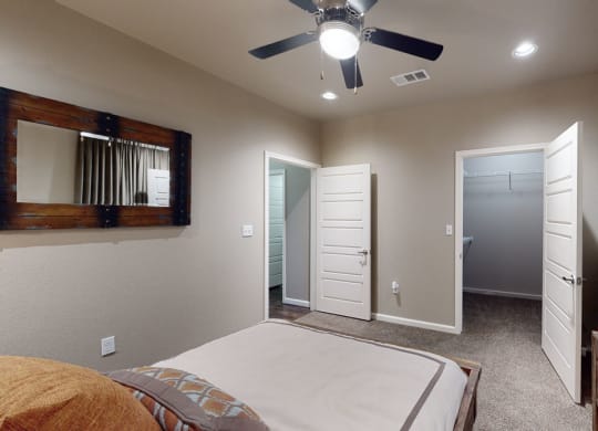 a bedroom with a ceiling fan and a mirror on the wall
