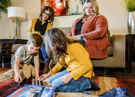A family playing a board game in a living room at Legends of River Oaks