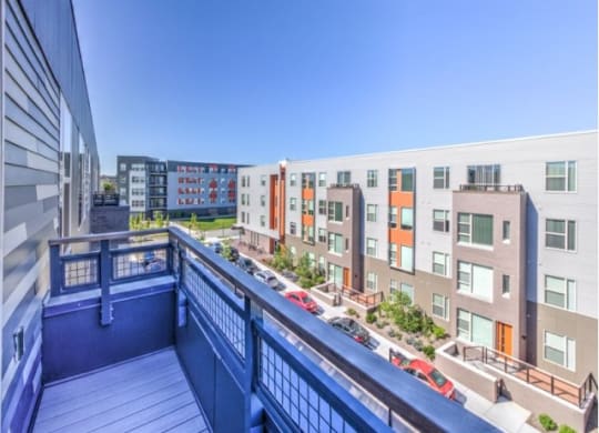 View from a balcony overlooking modern apartment buildings with colorful facades under a clear blue sky at Stitchweld Apartments.