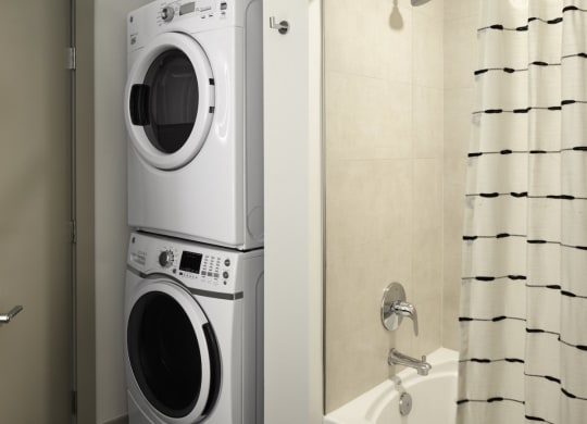 a front loading washer and dryer in a bathroom with a shower curtain