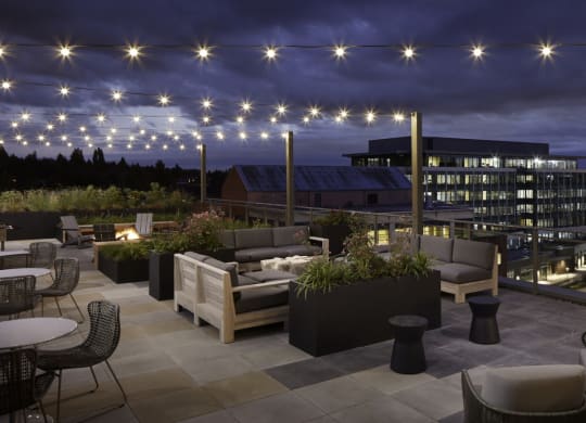 a rendering of the rooftop terrace at night with patio furniture and lights