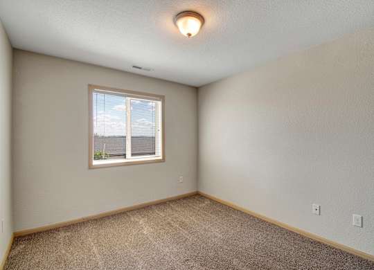 A room with a window and carpeted floor.