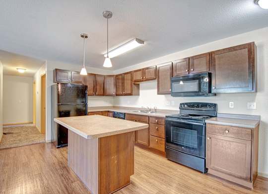 A kitchen with a black fridge, black stove, and black microwave.