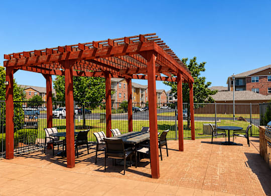 A red pergola with a table and chairs underneath it.