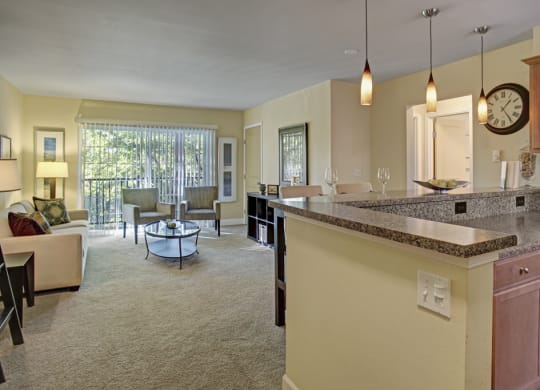 a kitchen with an island and a living room in the background