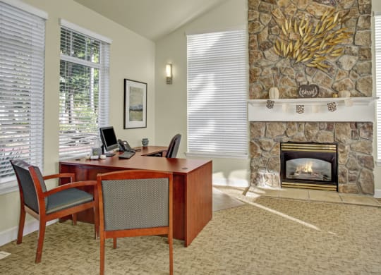 a room with a fireplace and a desk and chairs