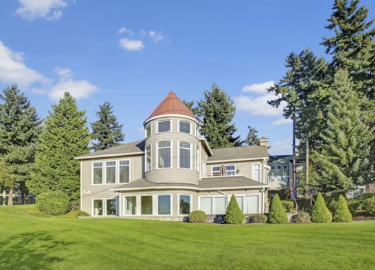 a large house with a tower on top of a grassy hill