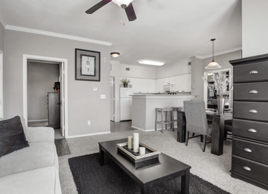 a black and white photo of a living room with a kitchen in the background