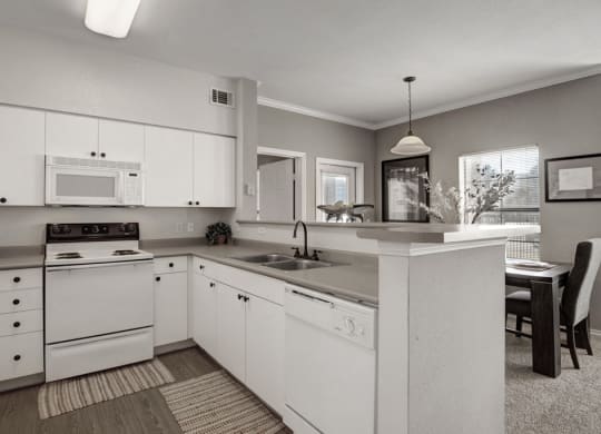 a black and white photo of a kitchen with white appliances and white cabinets